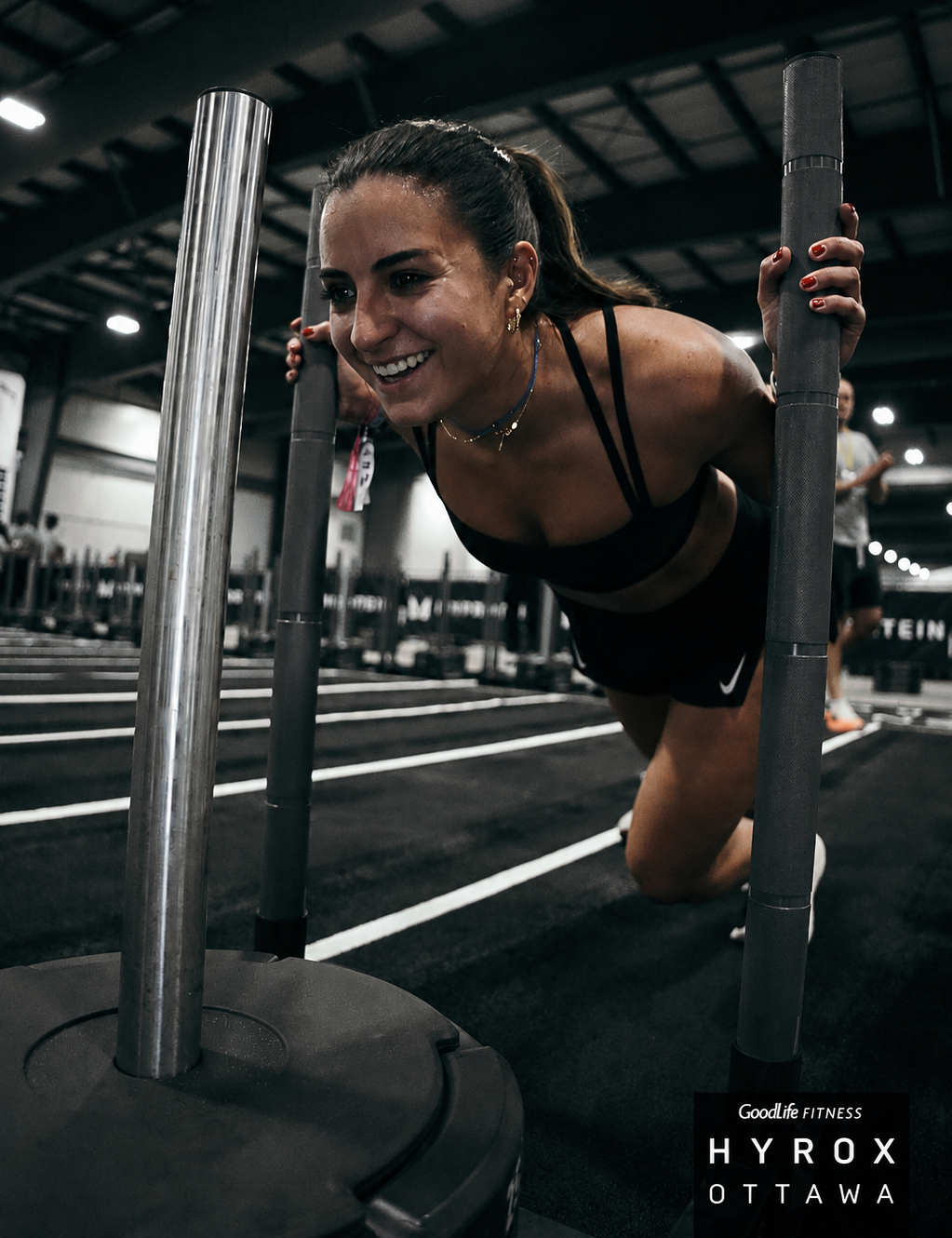 Carine pushing a weighted sled during a Hyrox competition